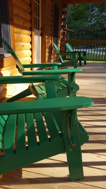Exterior shot of log cabin porch featuring 4 Adirondack chairs.