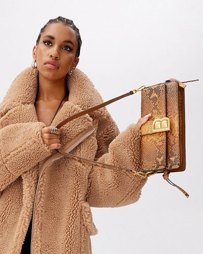 model in consignment designer fur coat holding consignment designer handbag 