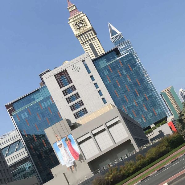 Modern buildings with a prominent clock tower under a clear blue sky.