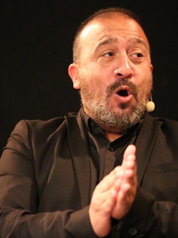 Man speaking and clapping hands on stage.