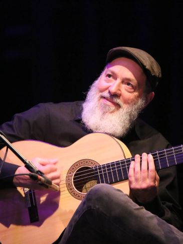 Bearded man playing guitar on stage