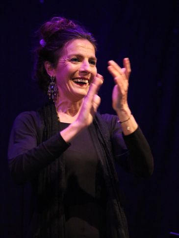 Woman clapping and smiling on stage.
