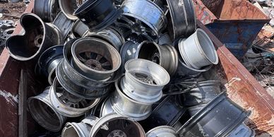 Pile of discarded car rims in a scrapyard.
