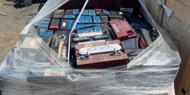 A pallet full of various used vehicle batteries wrapped in plastic.