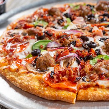 A delicious loaded pizza with various toppings on a metal tray.