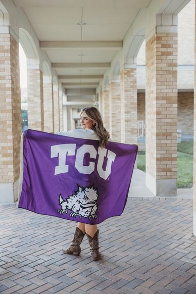Woman holding TCU flag in a corridor.