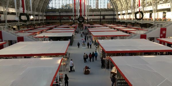 Spacious indoor market with white-roofed stalls and festive decorations under a large glass dome.