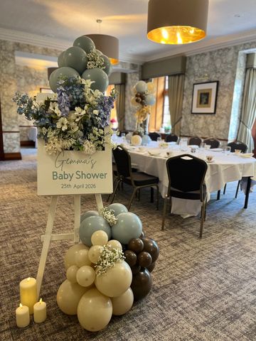 Elegant baby shower setup with balloons and flowers in a cozy dining room.