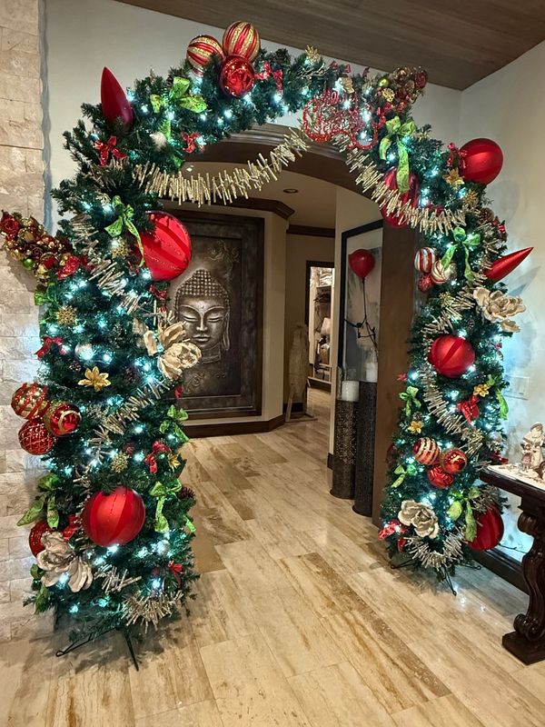 Festive Christmas arch decorated with red ornaments and lights indoors.