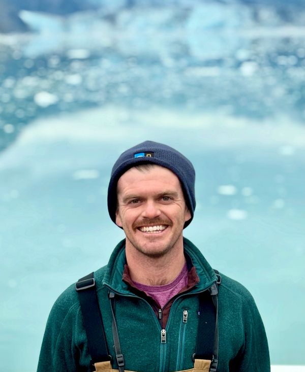 Smiling man in outdoor gear with icy water background.