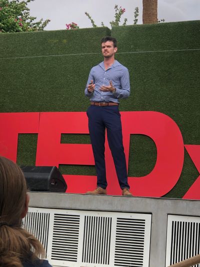 Man giving a TEDx talk on an outdoor stage.