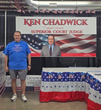 Man standing next to a campaign booth for Ken Chadwick, Superior Court Judge.