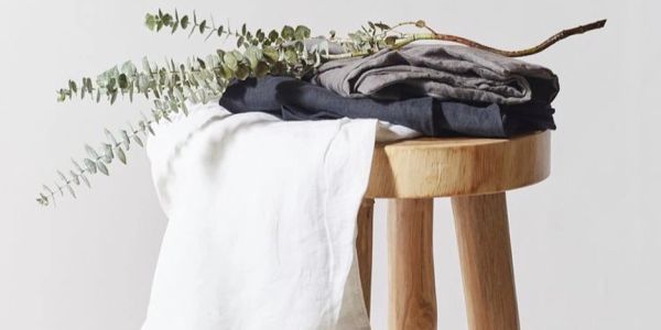 Stacked clothes and eucalyptus branches on a wooden stool.