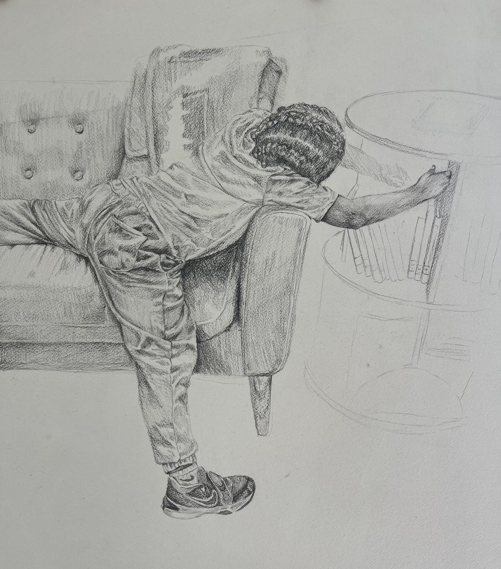 A child reaching for a book on a shelf while leaning on a sofa.