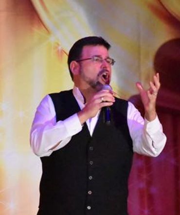 Man passionately singing into a microphone on stage.