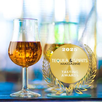 A glass of amber spirit next to a 2025 Tequila &amp; Spirits Magazine Tasting Awards emblem.