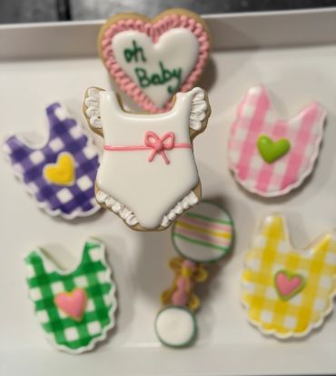 Decorative baby-themed cookies with bibs and a romper.