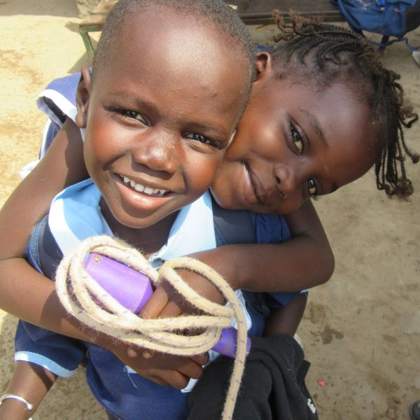 Two smiling children hugging each other closely outdoors.