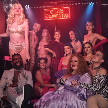Group photo at Club Cumming with people in glamorous and provocative outfits.