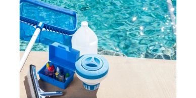 Pool cleaning and maintenance supplies beside a clear swimming pool.