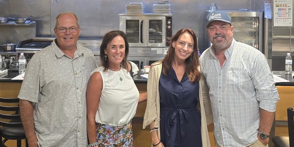 Four adults smiling in a kitchen setting.