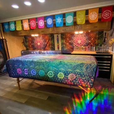 Healing space with colorful chakra-themed decorations and a treatment table.