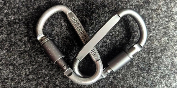 Two linked carabineers forming a heart shape on a textured surface.