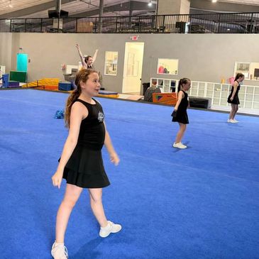 Young girls practicing dance or cheer routine indoors.