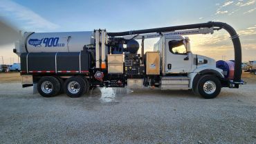 Large vacuum truck with industrial equipment under sunset sky.
