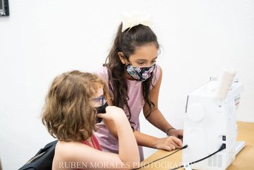 Girl helping camper with her sewing machine
