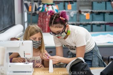 Girl helping a camper with her sewing project