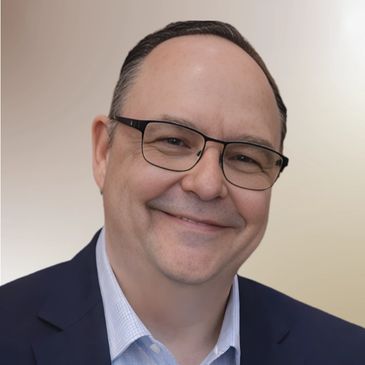 Smiling man with glasses in a suit.