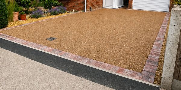 Newly laid gravel driveway bordered by bricks.