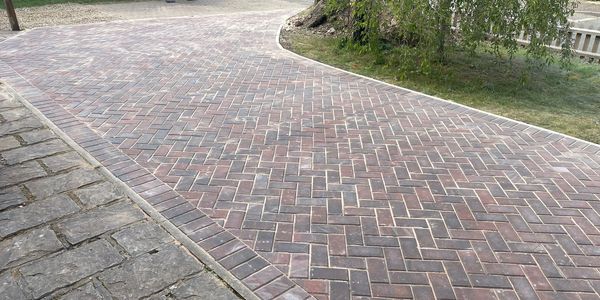 Curved brick paved pathway with adjacent stone pavement.
