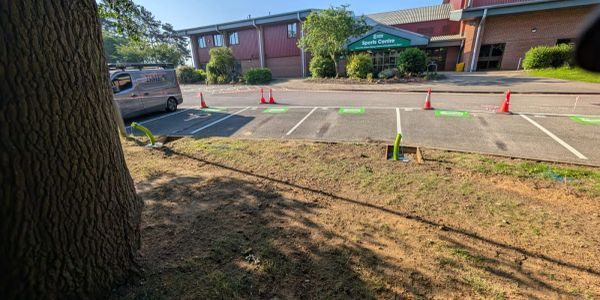 Sports centre entrance with parking spaces and orange cones.