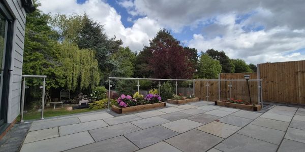 Spacious patio with raised flower beds and glass railing.