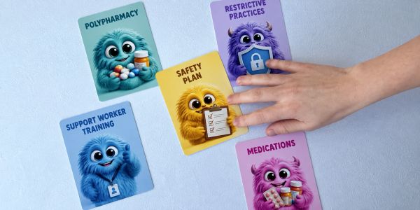 Hand arranging colorful cards with health-related terms and cute monster illustrations.