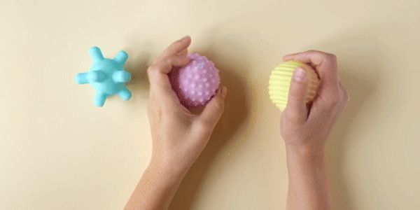Hands holding textured stress balls against a beige background.