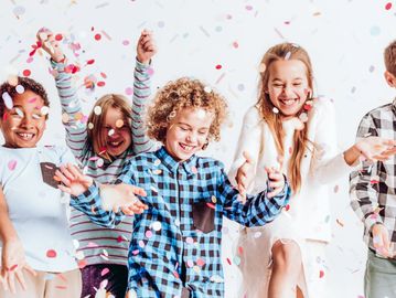 Happy children celebrating with colorful confetti in the air.