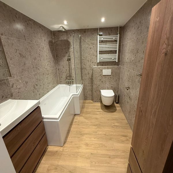 Moderne badkamer met houtlook vloer en marmeren wandtegels.