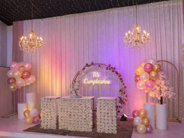 Elegant birthday party setup with floral decorations and chandeliers.