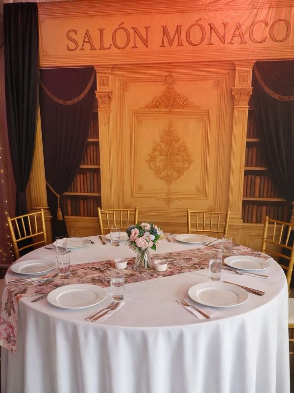 Elegant round table set with white plates and floral centerpiece in Salón Mónaco.