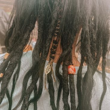 Close-up of decorated dreadlocks with beads and charms.