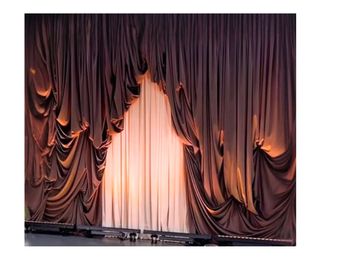 Dramatic stage curtains partially opened with warm light shining through.