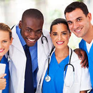 A diverse group of smiling healthcare professionals in blue scrubs and white coats.