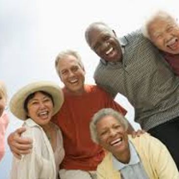 A group of diverse elderly friends happily posing together outdoors.