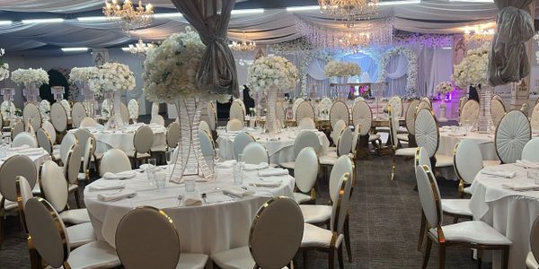 Elegant wedding reception setup with white floral centerpieces and round tables.