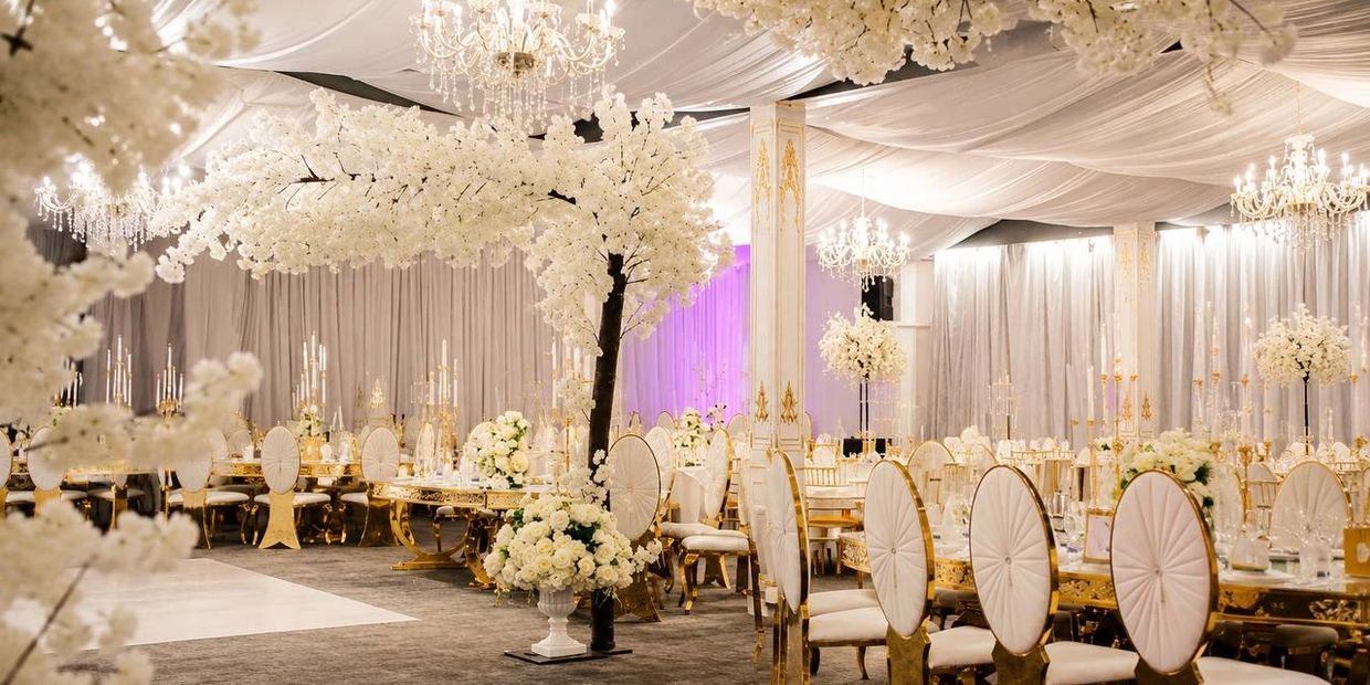 Elegant wedding reception setup with white floral decor and gold-accented furniture.