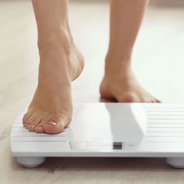 Person stepping on a bathroom scale to measure weight.