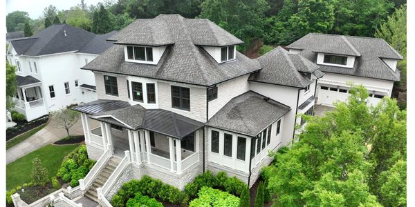 Large elegant house with manicured garden and multiple roof sections.